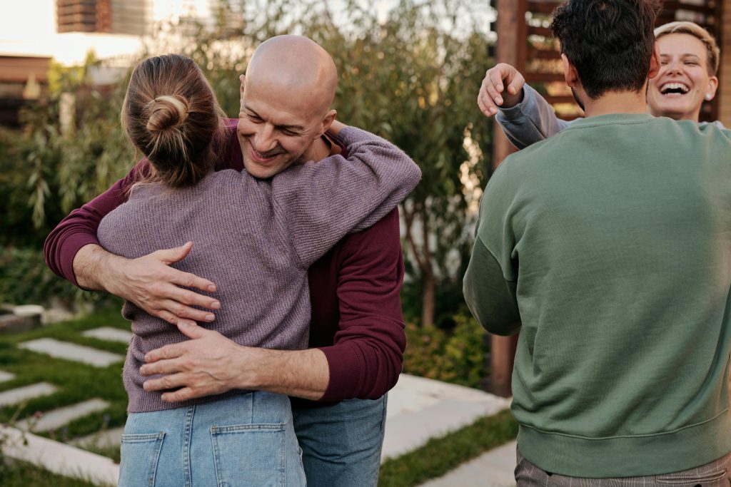 pexels photo 5638602 5638602 Cheerful friends hugging and smiling while spending time together in suburban yard during weekends